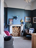 Cheminée remplie de bûches dans le salon peint en bleu moderne