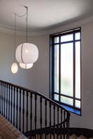 Luminaire suspendu blanc au-dessus de l'escalier peint en noir et blanc