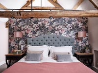 Mur de caractéristiques florales derrière le lit dans la chambre de campagne