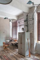 Bureau, chaise et armoire avec sols décapés et murs en plâtre nu