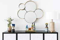Buffet noir et blanc et groupe de miroirs circulaires sur le mur