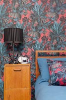 Meuble de chevet en bois vintage dans une chambre moderne avec papier peint coloré