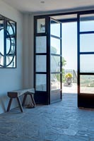 Portes vitrées à cadre noir et sol en pierre dans le couloir moderne