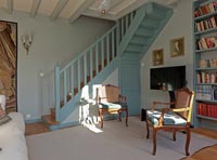 Escalier peint en bleu et bibliothèque assortie dans le salon de pays