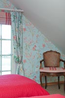 Fauteuil en bois contre mur tapissé floral coloré dans la chambre