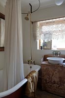 Douche dans la baignoire et lavabo décoratif dans la salle de bains de style vintage