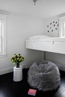 Lit superposé blanc et coussin de sol en fourrure dans une chambre d'enfant moderne