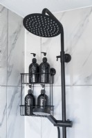 Détail de la pomme de douche noire et des carreaux de marbre gris dans la salle de bains moderne