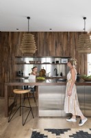 Famille dans une cuisine moderne à aire ouverte avec armoire intégrée en bois et acier inoxydable