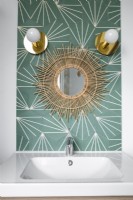 Miroir Sunburst sur mur à motifs au-dessus du lavabo de la salle de bain