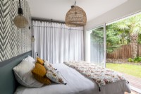 Chambre à coucher moderne avec portes-fenêtres ouvertes sur le jardin en été