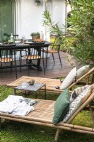 Fauteuils inclinables en bambou et salle à manger extérieure dans un petit jardin moderne