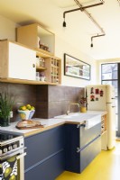 Cuisine rétro moderne avec sol en caoutchouc jaune, armoires bleues, contreplaqué, éclairage en cuivre