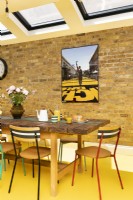 Salle à manger moderne avec briques apparentes, sol en caoutchouc jaune, table et chaises recyclées