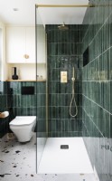 Salle de bain moderne et contemporaine avec carreaux verticaux vert, carreaux de sol en terrazzo et raccords en laiton, robinets