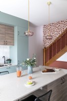 Cuisine pastel moderne avec escalier coloré sur le mur du fond