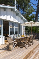 Salle à manger extérieure sur une terrasse surélevée à côté de la maison côtière en été