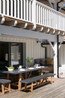 Table à manger grise et bancs sur la terrasse à côté de la maison