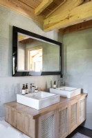 Éviers jumeaux sur l'unité en bois dans la salle de bains moderne de pays