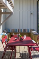 Table à manger rouge et chaises sur terrasse avec banquette intégrée