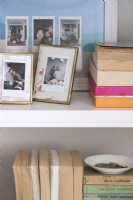 Détail de photographies de famille encadrées et de livres sur des étagères