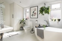 Salle de bain moderne avec des œuvres d'art sur le mur et beaucoup de plantes d'intérieur