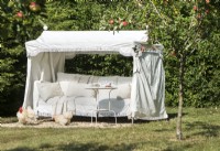 Grand lit de repos avec baldaquin dans le jardin de campagne