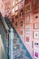 Escalier peint en bleu avec chemin d'escalier, murs roses et présentoir d'art mural de style salon