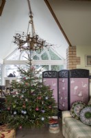 Arbre de Noël dans le salon avec écran rose derrière et toit apex