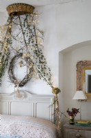 Chambre cottage décorée pour Noël, mobilier champêtre et guirlande de feuillage au dessus du lit