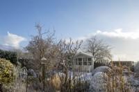 Jardin enneigé dans le village de Devon, avec maison d'été et haie en forme