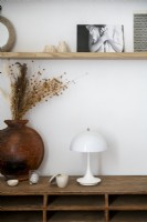 Lampe blanche et vase en bois de fleurs séchées sur meuble en bois
