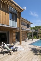 Fauteuils inclinables sur la terrasse à côté de la piscine - maison en bois moderne