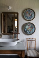Détail du lavabo de la salle de bain et des peintures florales circulaires sur le mur