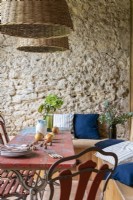 Table à manger extérieure avec coussins sur banquette intégrée par mur de pierre