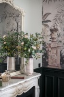 Arrangement de fleurs sur la cheminée en marbre à côté d'un mur tapissé
