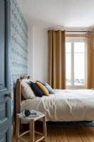 Chambre à coucher moderne avec papier peint à motifs bleus et rideaux moutarde