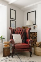 Salon contemporain à aire ouverte dans un cottage de Cornouailles. Doté d'un poêle à bois et d'un fauteuil à oreilles en cuir rouge.