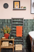 Radiateur sèche-serviettes noir dans une salle de bains carrelée de vert