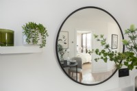 Détail d'un miroir rond sur un mur reflétant l'intérieur d'un appartement