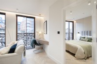 Coin de salon dans un appartement moderne avec bureau en bois intégré et vue sur une chambre