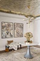 Détails de la chambre avec papier peint en feuilles de métal au plafond décoré d'un guéridon, d'un banc et d'œuvres d'art.