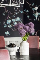 Détails des fleurs violettes et des raisins sur la table de la salle à manger et le papier peint floral.