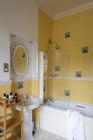 Salle de bains jaune de maison de campagne avec les murs carrelés