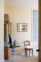 Chambre de style vintage avec des murs peints en crème pâle, une armoire et une porte en pin.