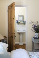 Porte en pin menant à la salle de bain attenante, de la chambre de style vintage peinte en crème