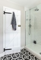 Porte de style grange originale dans une salle de bains moderne avec cabine de douche