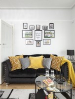 Canapé noir et affichage de photos encadrées dans un salon moderne