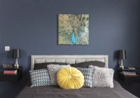 Variété de coussins sur le lit avec une peinture de paon sur le mur au-dessus