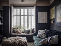 Salon sombre avec canapé en velours, siège de fenêtre et volets de plantation